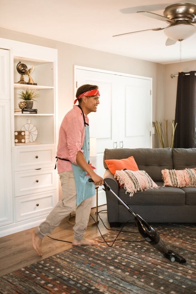 Smiling man with a headband vacuuming a modern living room.